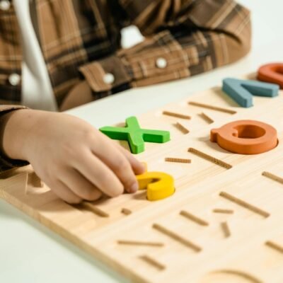 Close-up of a child playing with a colorful alphabet puzzle board.